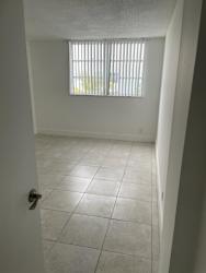 A white tiled room with a door and a window with blinds.