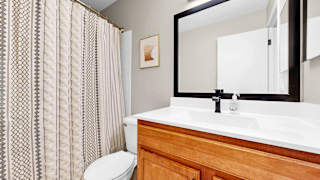A bathroom with a toilet, sink, and a mirror.