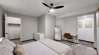 A bedroom with a bed, chair, and desk.