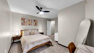 A bedroom with a bed, a chair, and a ceiling fan.
