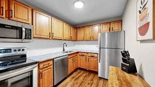A kitchen with wooden cabinets and a stainless steel refrigerator.