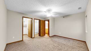 A room with a carpeted floor and a ceiling fan.