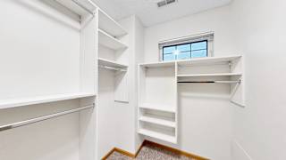 A white walk-in closet with shelves and a window.