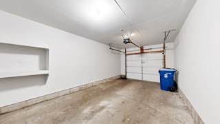 A white wall with a blue bin and a pipe.