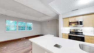 A kitchen with a white countertop and wooden cabinets.