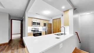 A modern kitchen with a white countertop and wooden cabinets.
