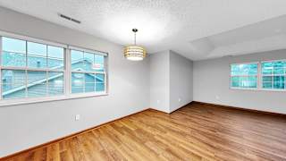A room with wooden floors and two windows.