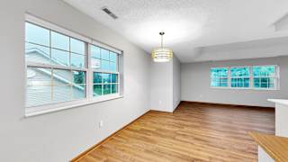 A room with wooden floors and a large window with a view of a house.
