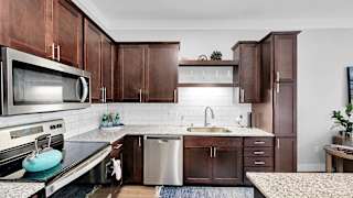 A kitchen with brown cabinets and a white backsplash.