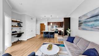A modern living room with a dining area and a kitchen in the background.