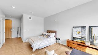 A bedroom with a bed, a nightstand, a chair, and a painting on the wall.