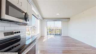 A kitchen with a black stove top oven and a black microwave above it at The Bessemer at Seward Commons Apartments, Minnesota, 55404