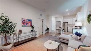 A living room with a couch, a table, and a painting on the wall at The Bessemer at Seward Commons Apartments, Minneapolis, Minnesota