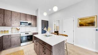 A modern kitchen with a white island and wooden cabinets.