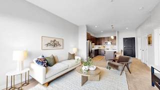 A living room with a white couch, a coffee table, and a painting on the wall.