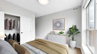 A bedroom with a bed, a plant, and a wardrobe.