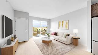 A living room with a white sofa, a wooden coffee table, and a flat-screen TV mounted on the wall.
