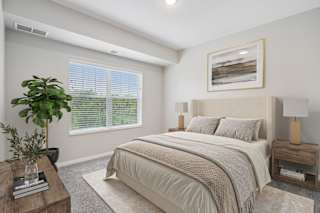 A well-lit bedroom with a large bed and a potted plant.