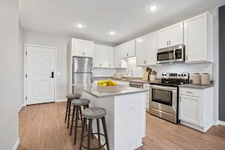 A kitchen with white cabinets and a wooden floor.