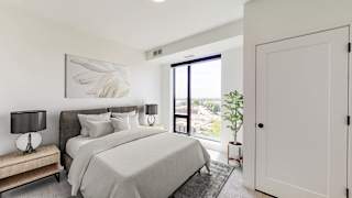 a white bedroom with a large bed and a door to a balcony at The Mason, Minnesota, 55114