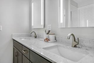 a bathroom with two sinks and two mirrors at The Mezz at West Lake Quarter, Minneapolis, MN 55416