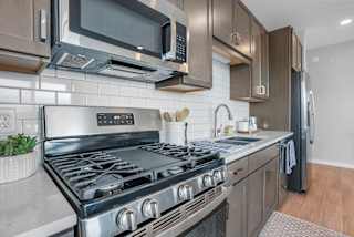 a kitchen with a stove top oven next to a sink and a microwave at The Mezz at West Lake Quarter, Minneapolis