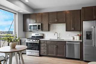 a kitchen with dark wood cabinets and stainless steel appliances at The Mezz at West Lake Quarter, Minneapolis, MN 55416
