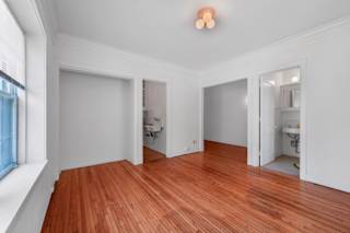 a bedroom with a hardwood floor and white walls at The Park Apartments, Minneapolis, MN