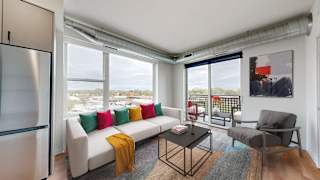 an open living room with a white couch and a table with colorful pillows at Tyler Street Stacks, Minneapolis, 55413