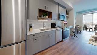 a kitchen with white cabinets and a stainless steel refrigerator at Tyler Street Stacks, Minnesota, 55413