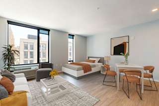 A modern bedroom with a large bed, a couch, a chair, a coffee table, and a painting on the wall.