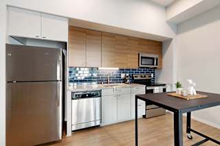 A modern kitchen with a stainless steel refrigerator and white cabinets.