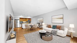 A modern living room with a kitchen in the background.