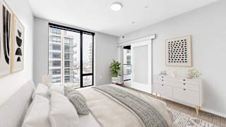 A bedroom with a large bed and a window overlooking a city.