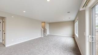 A spacious room with a carpeted floor and a staircase leading to another level.