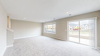 A spacious room with a carpeted floor and large windows.