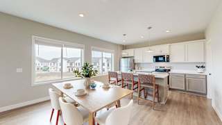 A dining room with a table set for four and a kitchen area in the background.