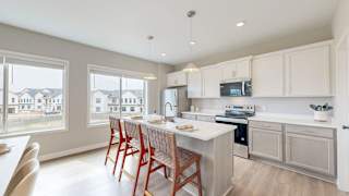 A kitchen with white cabinets and a large island with a sink.