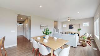 A dining room with a wooden table and white chairs.