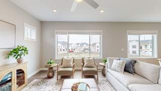 A living room with a couch, chairs, and a ceiling fan.