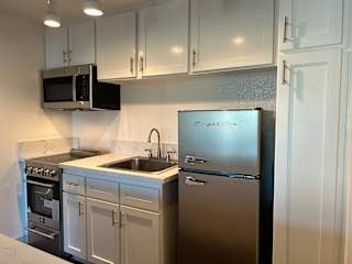A kitchen with a stainless steel refrigerator and white cabinets.
