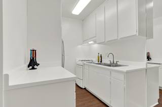 a kitchen with white cabinets and a sink and a refrigerator at Olive Tree Apartments, California, 90503
