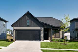 A modern house with a garage door and a tree in front.
