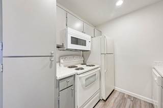 A small kitchen with a white fridge, microwave, and stove.
