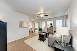 A living room with a ceiling fan and a grey couch.