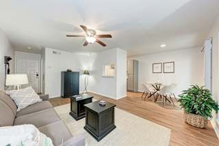 A living room with a grey couch, a black cabinet, a coffee table, and a ceiling fan.