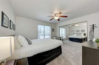 A bedroom with a large bed and a ceiling fan.