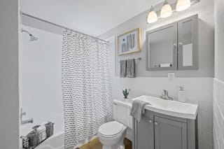 A white bathroom with a toilet, sink, and shower at Huntley Ridge Apartments, Kettering, OH