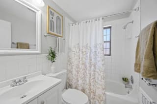 A white bathroom with a toilet, sink, and shower at Huntley Ridge Apartments, Kettering 45419