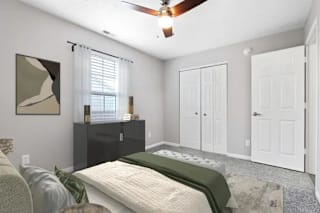 A bedroom with a bed, a ceiling fan, and a window with blinds at Parkview of Lebanon Apartments, Lebanon, IN, 46052